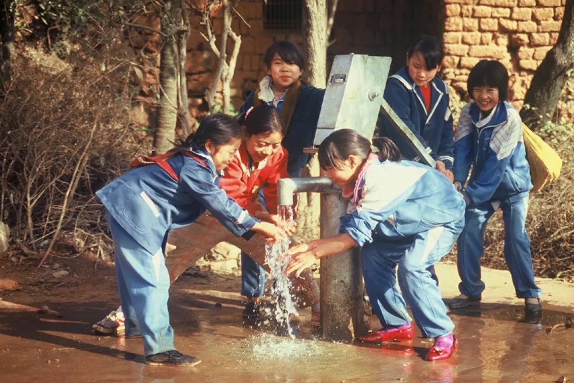 一群学校女生使用联合国儿童基金会提供的手压泵洗手。