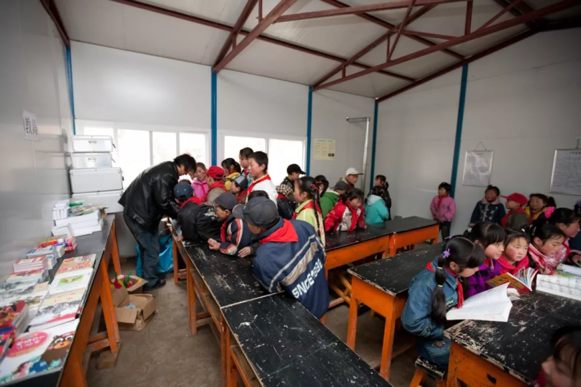 Children in Caochuan Primary School wait to sign out sports equipment as others are reading new library books.