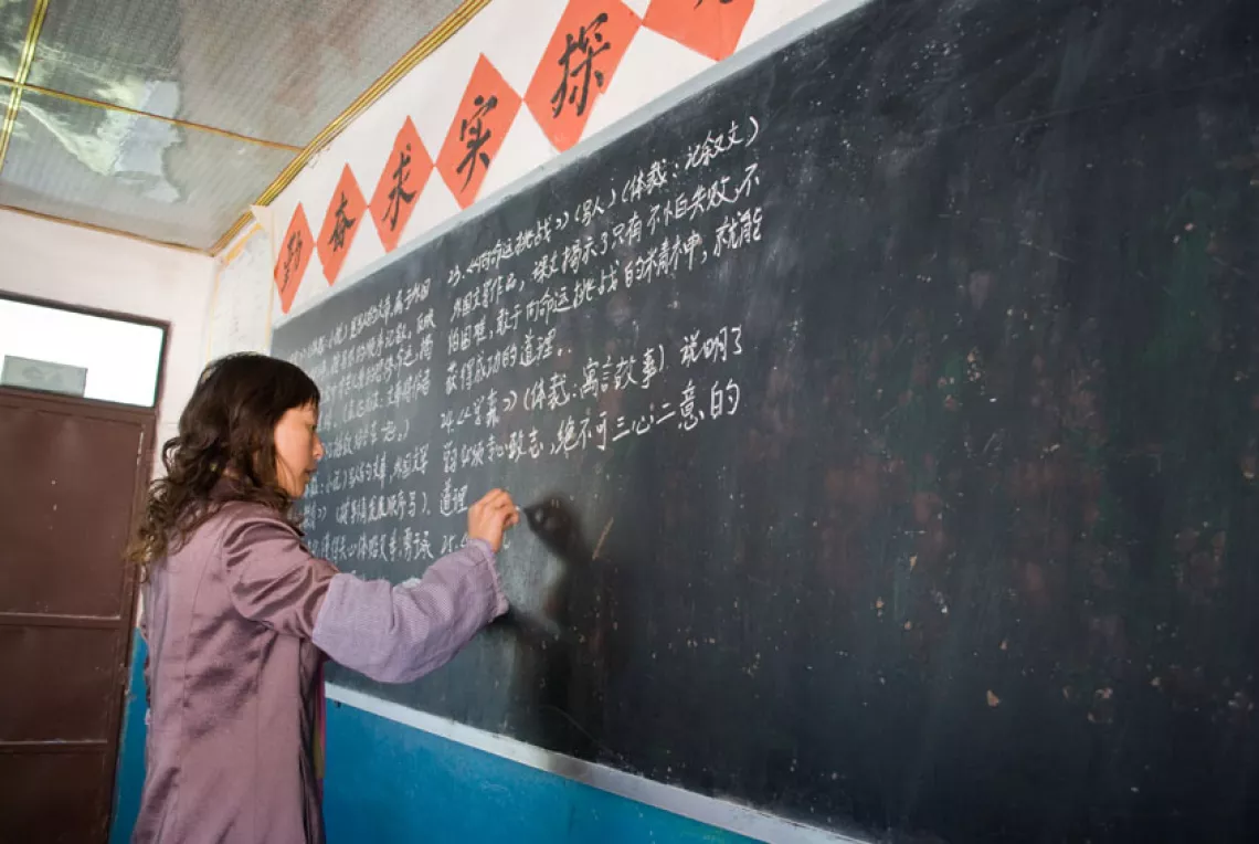 A teacher writes key points on the blackboard for the students to copy.