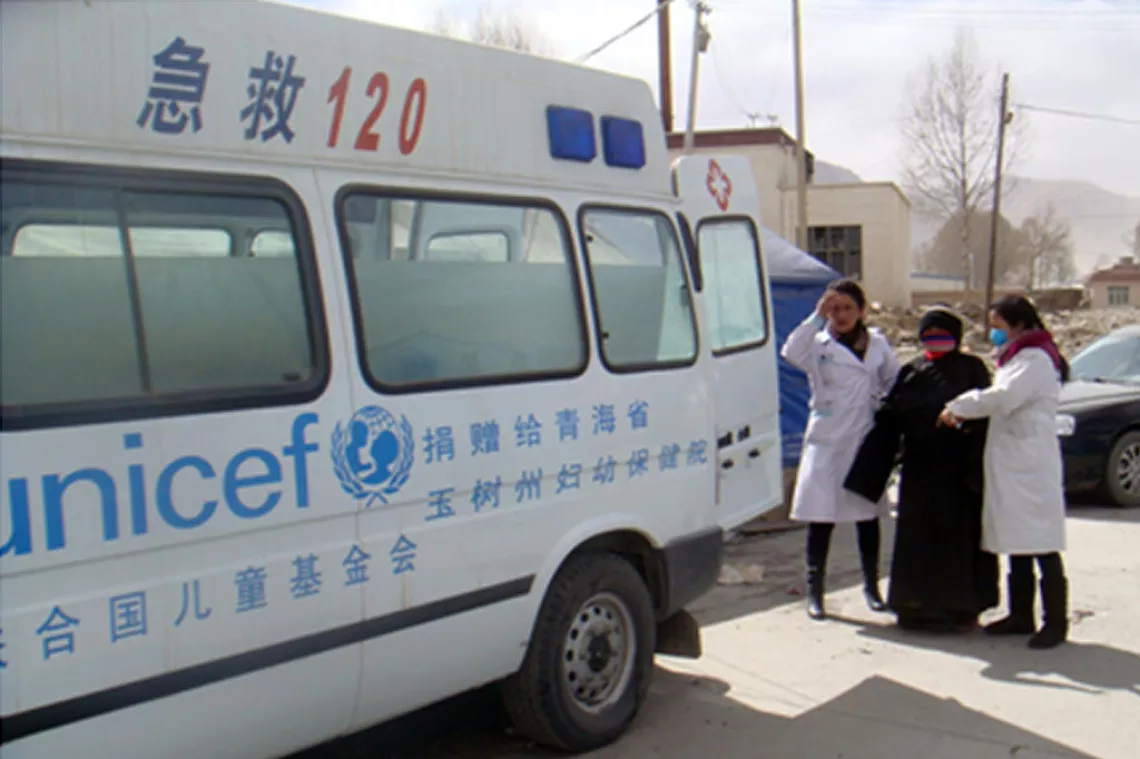 在中国青海省，医务人员帮助一位有并发症的孕妇登上救护车。