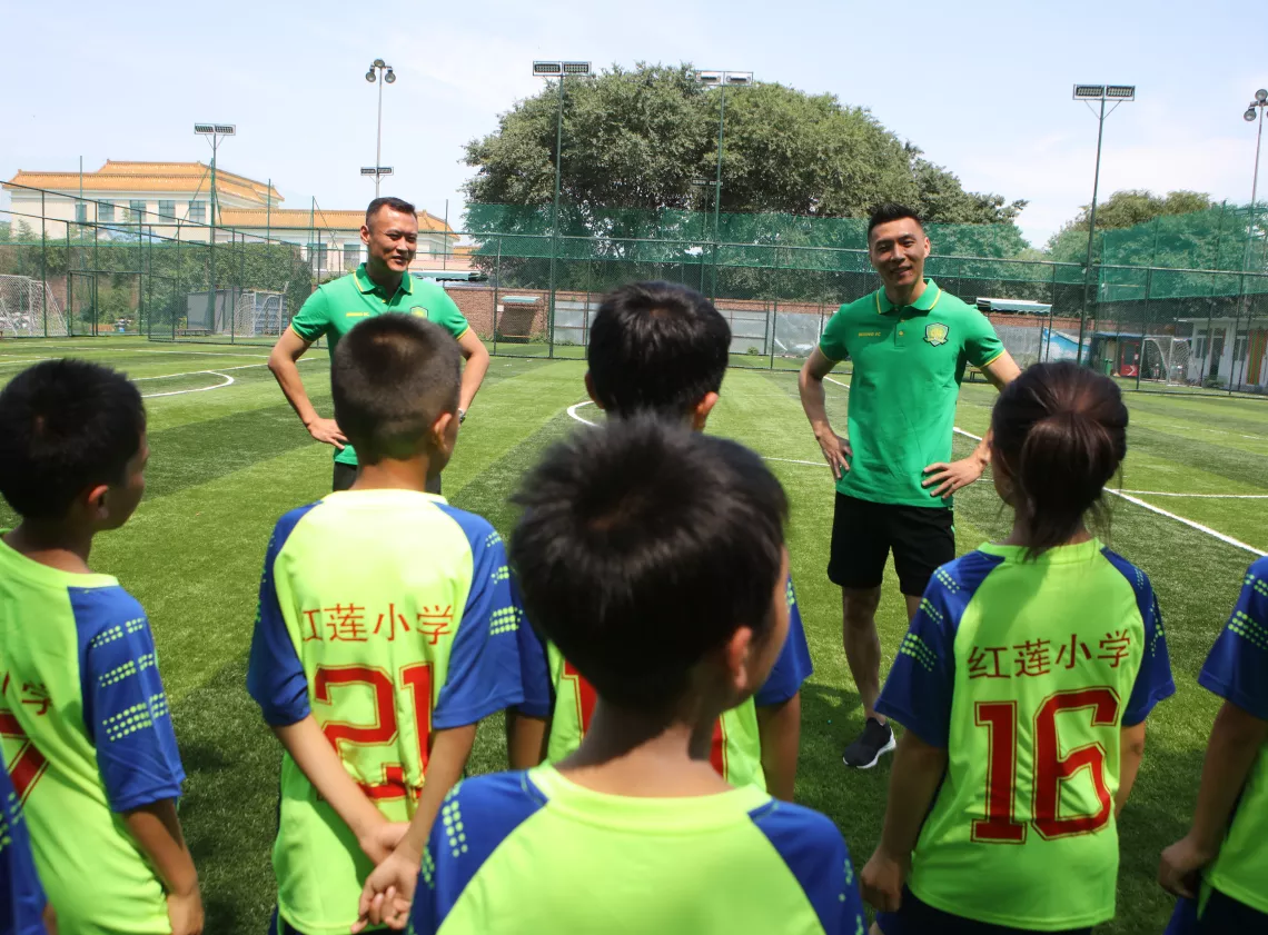 世界杯期间的一个下午，20名红莲小学的孩子们迎来了两位同样热爱足球的大朋友——北京中赫国安足球俱乐部功勋队长、商务总监徐云龙（左）和现任队长于大宝（右）。