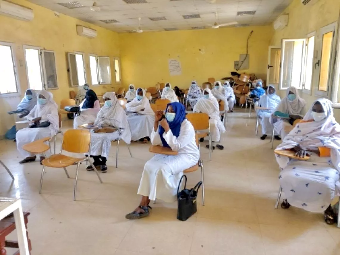 A classroom with Sudanese mid-wives practicing social distancing and wearing face masks.