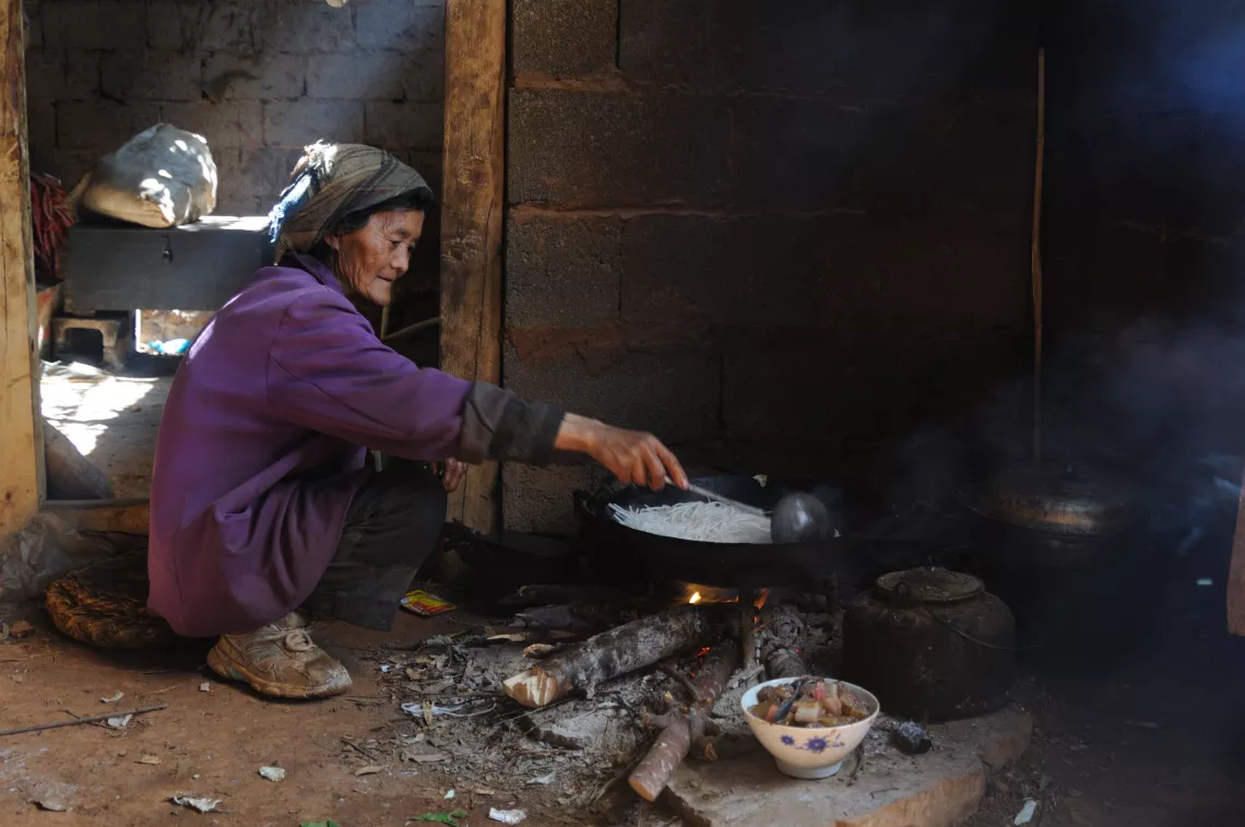An old woman cooks lunch at her home in Shubo Village, Shizong County.