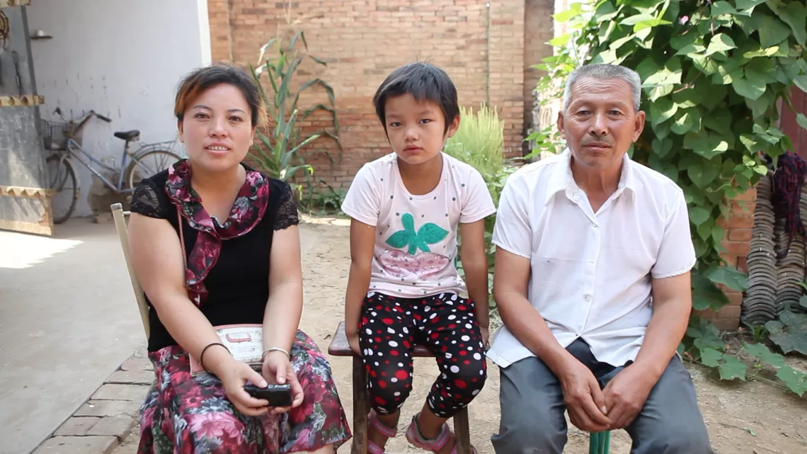 梅红芳（左）是这个村的儿童福利主任。她几乎每周都来看盼盼，帮着做做家务，跟她聊聊天。