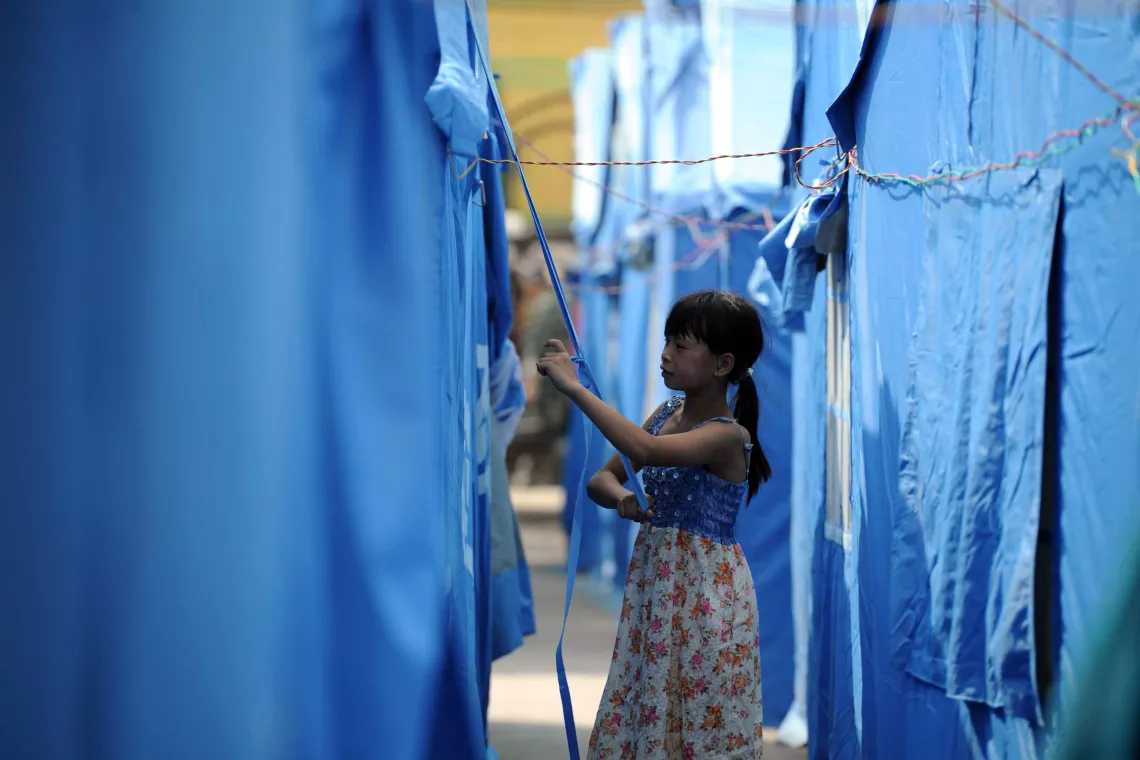 A girl stands in front of the temporary shelter in Yiliang County, Yunnan Province.