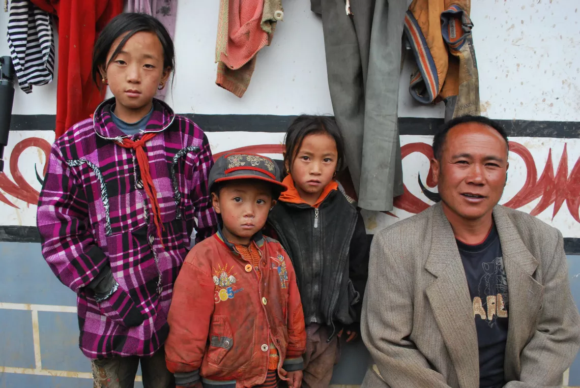 凉山州金阳县的一名村儿童福利主任（右一）与他负责帮助的三名孤儿在一起。