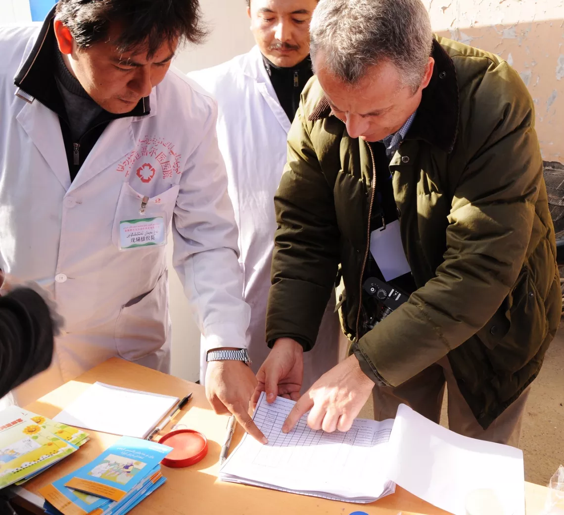 UNICEF programme specialist Etienne Poirot (right) inspects vaccination records from a mobile vaccination station in Yutian county.