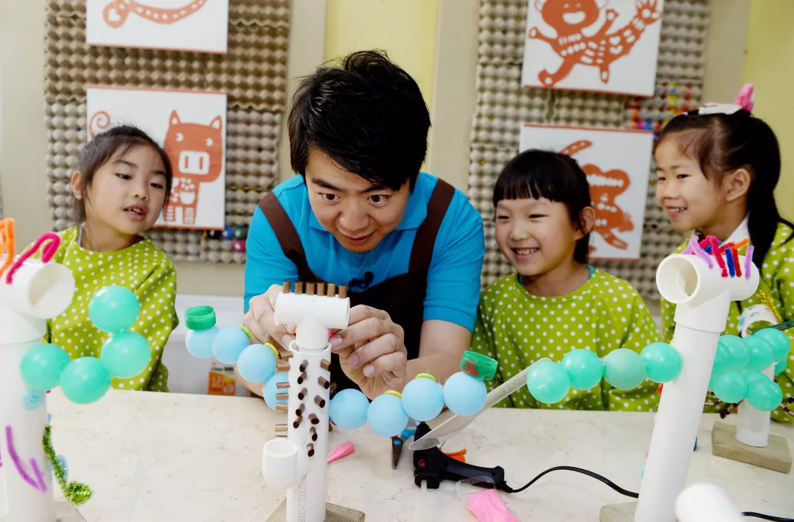Lang Lang and children jointly make a doll with recycled materials including straws, PVC pipes and bottle caps.