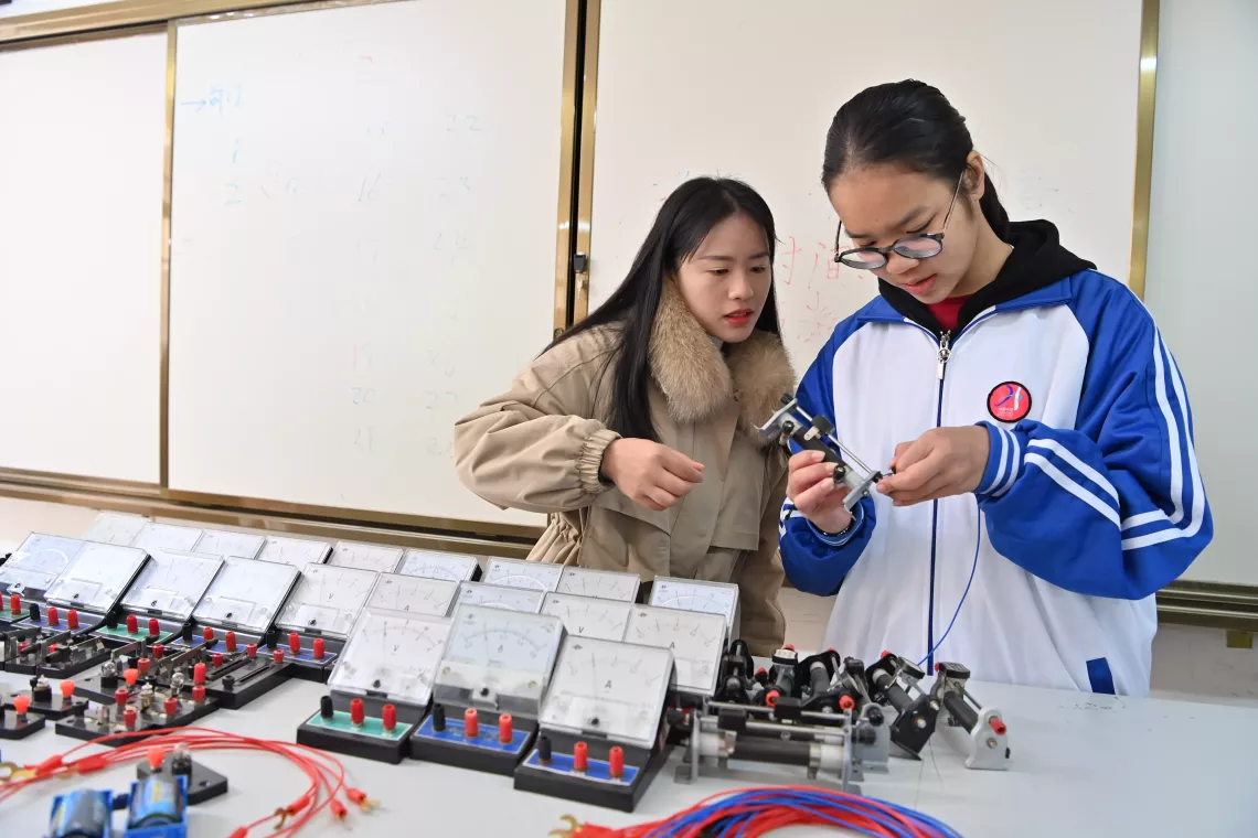 广西天等县华隆中学学生韦李敏（右）和老师刘玉萍在做电阻实验（2023年12月27日摄）