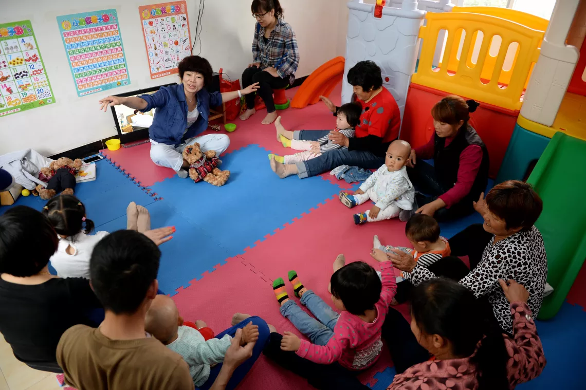 Li Tong, the ECD programme’s advisor and a child-rearing expert, shows caregivers in the Ai community ECD centre how to play with their children at home.