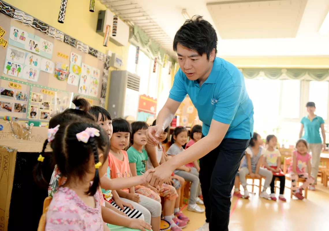 Lang Lang, United Nations Messenger of Peace and pianist, greets children during a recent visit to Fuli Taoyuan Kindergarten on the fringe of Beijing in May 2014.
