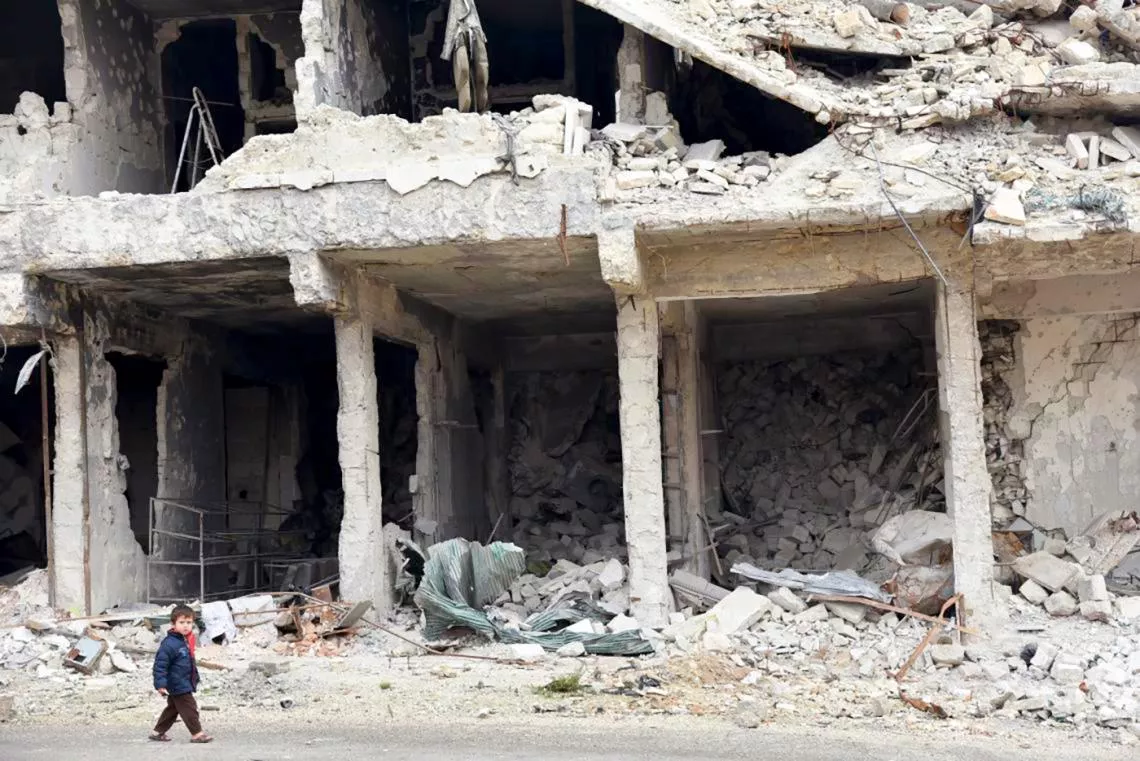 叙利亚阿勒颇，一名儿童走过建筑物废墟。