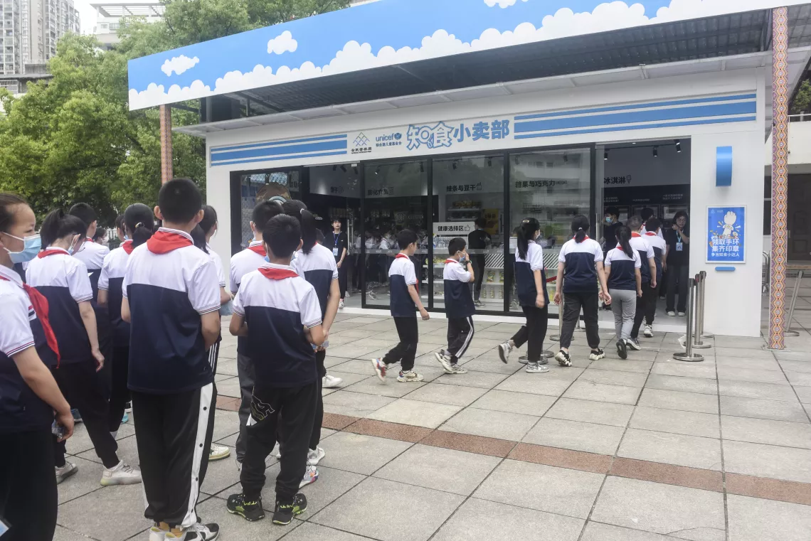 Students line up to enter UNICEF’s ‘Know Your Food’ Convenience Store at the Enshi Experimental Primary School in Enshi, Hubei Province, on 21 May 2022.