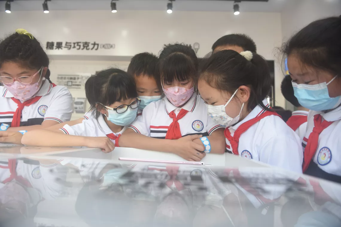 Children watch educational videos inside UNICEF’s ‘Know Your Food’ Convenience Store at the Enshi Experimental Primary School in Enshi, Hubei Province, on 20 May 2022.