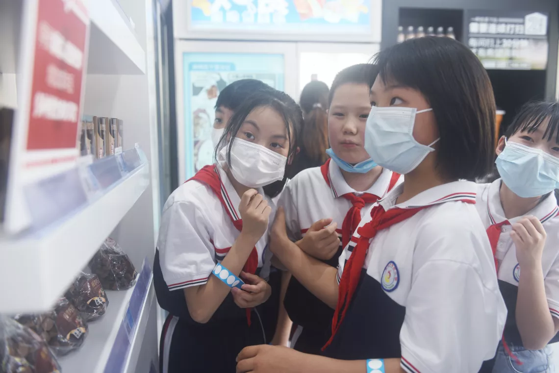 Students read the warning information on the potential health hazards of frequent consumption of foods high in sugar inside UNICEF’s ‘Know Your Food’ Convenience Store at the Enshi Experimental Primary School in Enshi, Hubei Province, on 20 May 2022.