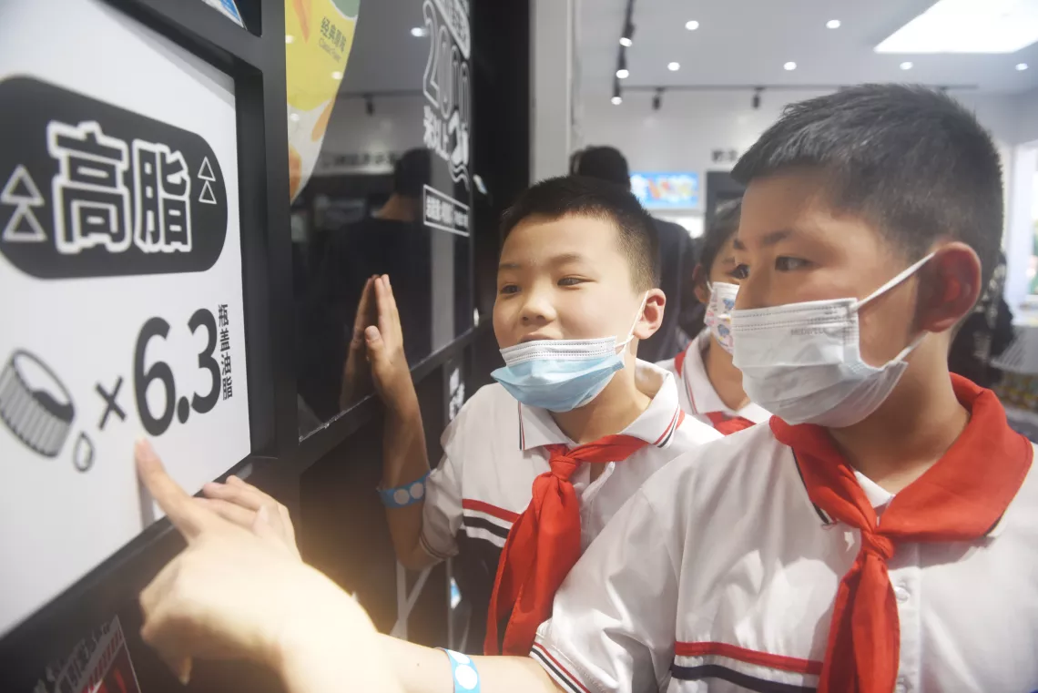 Students read how much fat a pack of potato chips contain through an interactive installation inside UNICEF’s ‘Know Your Food’ Convenience Store at the Enshi Experimental Primary School in Enshi, Hubei Province, on 20 May 2022.