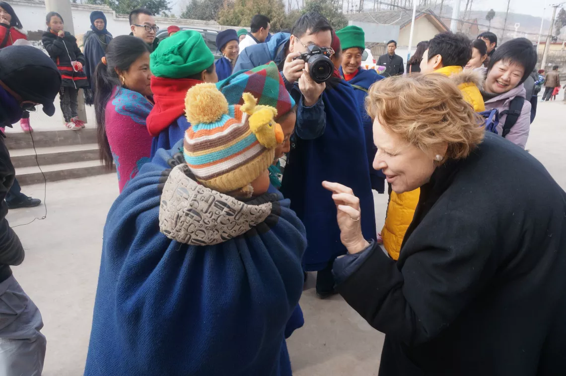 2015年1月14日，在四川省凉山彝族自治州昭觉县，联合国儿童基金会驻华代表麦吉莲（Gillian Mellsop）和一名当地彝族妇女和她的孩子打招呼。