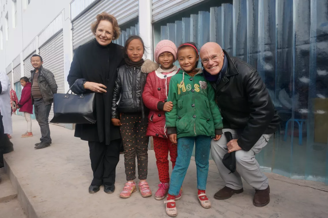 2015年1月14日，在四川省凉山彝族自治州昭觉县，联合国儿童基金会驻华代表麦吉莲（Gillian Mellsop）（左一）和联合国儿童基金会驻东亚及太平洋地区主任丹尼尔•图尔（Daniel Toole）（右一）与当地儿童合影。