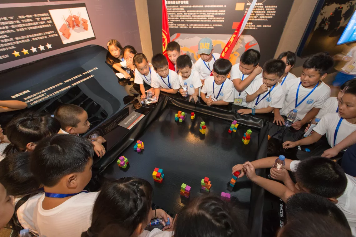 Children pile building blocks on the surface of a seismic wave simulator at the Sichuan Disaster Prevention and Reduction Museum in Chengdu.