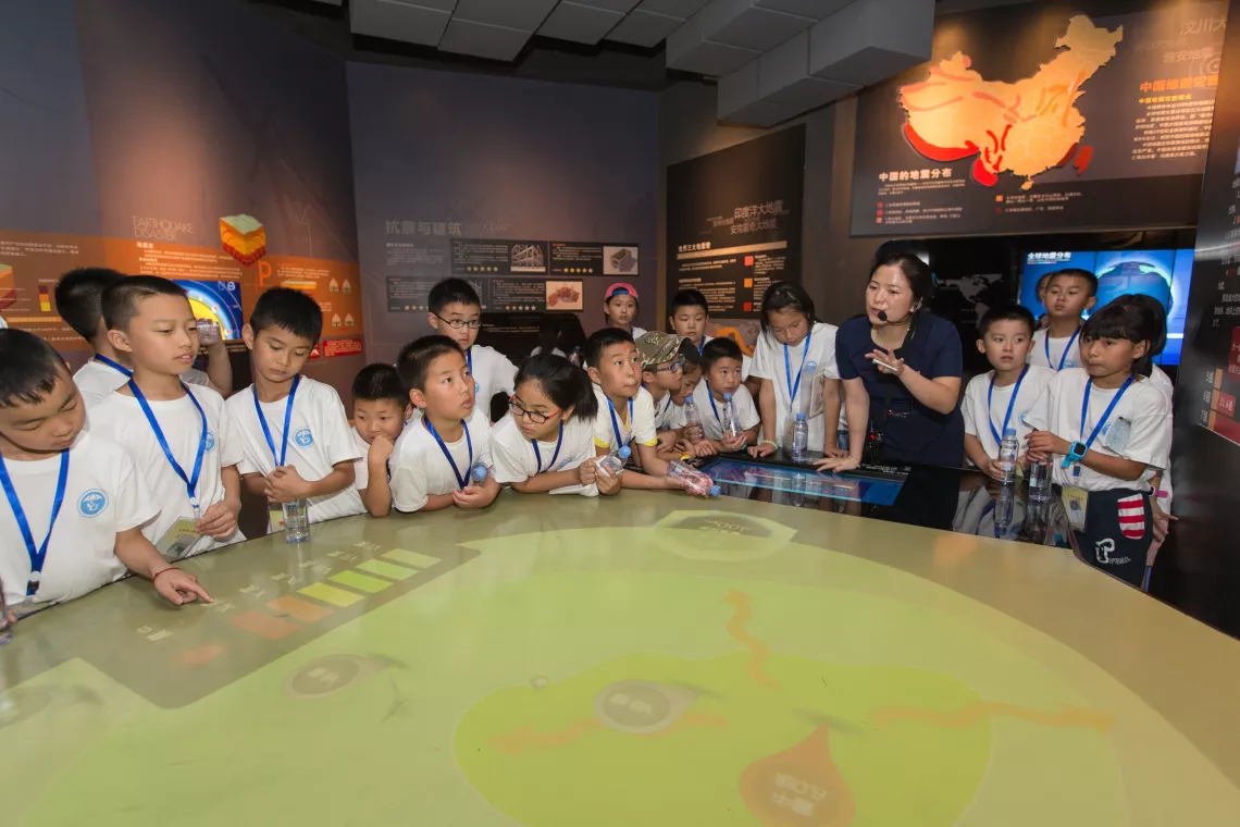 A museum guide shows the children why and how an earthquake occurs at the Sichuan Disaster Prevention and Reduction Museum in Chengdu.