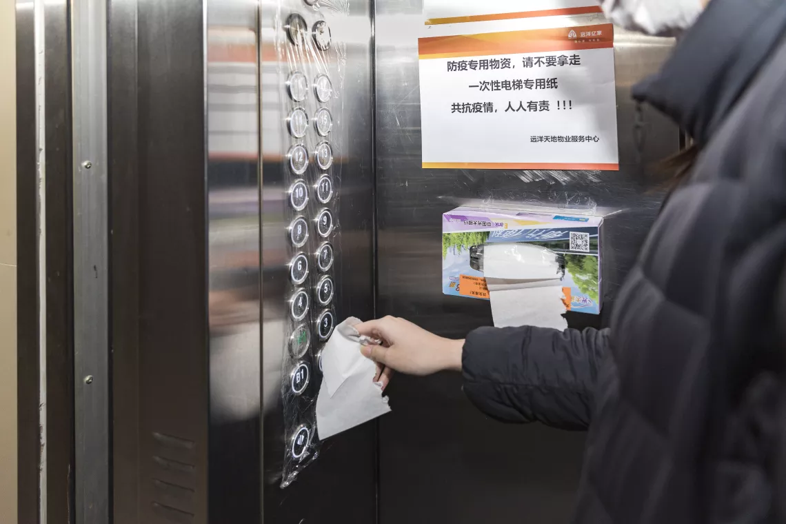 Xiaoyu presses the button in the elevator with a tissue, as she goes downstairs to exercise.