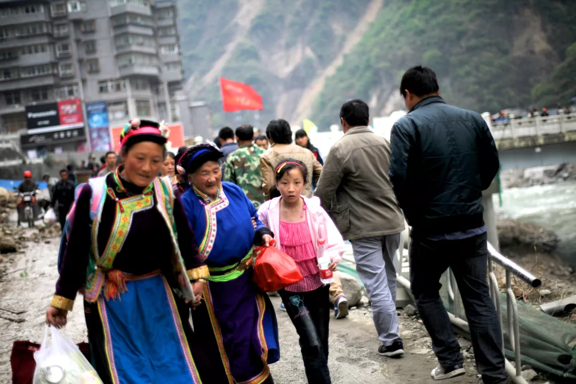 2013年4月22日，四川省雅安宝兴县，一个女孩跟着奶奶和妈妈从山体滑坡处赶往安置区。