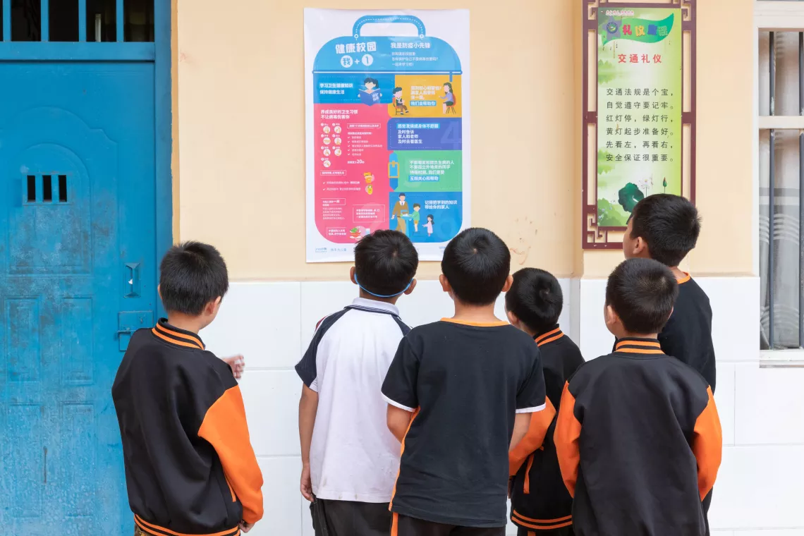 2020年6月3日，重庆忠县任家镇义兴学校的学生在校园内阅读由联合国儿童基金会与中华人民共和国教育部及中国疾病预防控制中心制作的包含安全返校实用信息的海报。