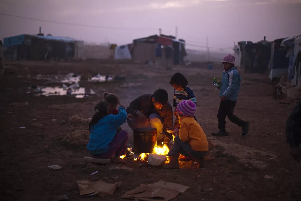On 18 January, children gather around a fire in a makeshift encampment for Syrian refugees, near the town of Baalbek in the eastern Bekaa Valley, near the Syrian border.