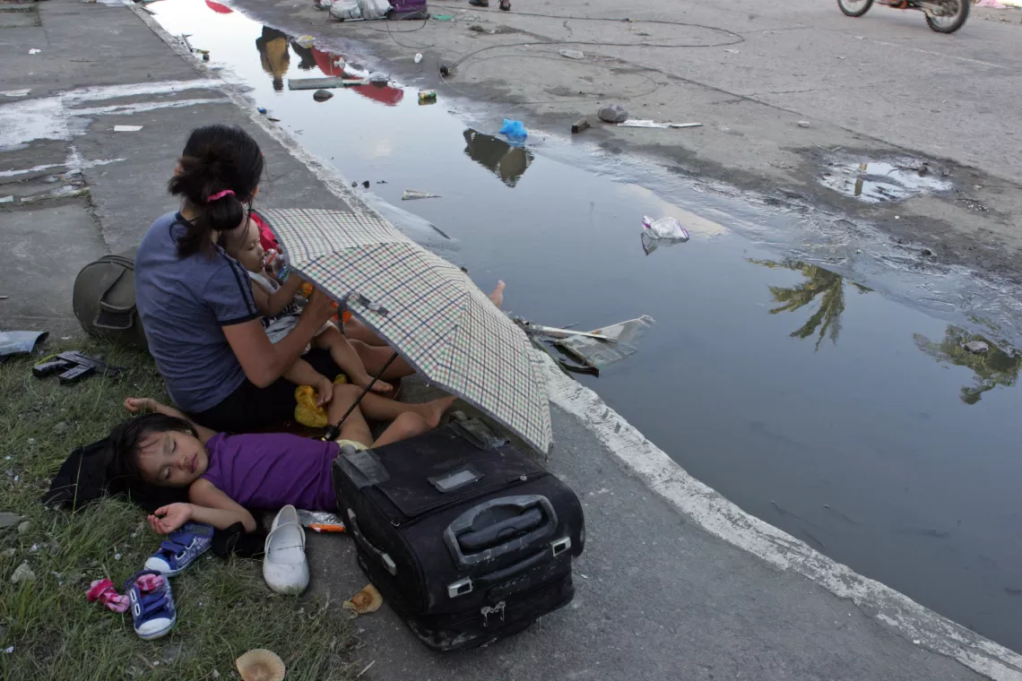 On 10 November, a woman and her children, who have been displaced by Super Typhoon Haiyan, rest on the side of a partially flooded street in Tacloban City – one of the areas worst affected by the disaster.