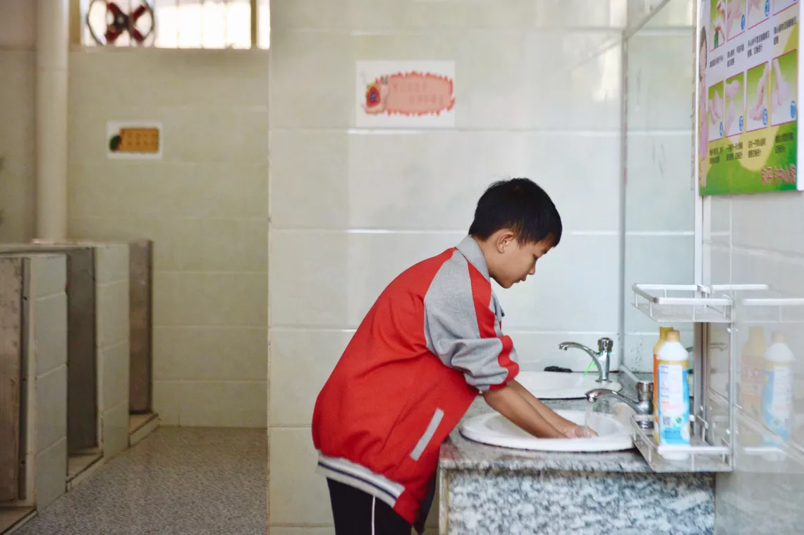 在广西三江侗族自治县和平乡中心小学，一名学生在学校卫生间洗手。
