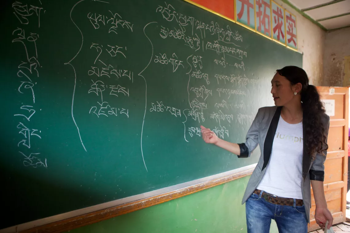 考察团观摩了一节藏语课，老师在黑板上书写优雅的藏文。