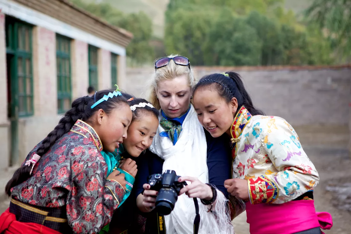 三名身着藏族传统服装的女学生簇拥着立陶宛国家委员会主席约维塔•马雅斯卡特，看着相机屏幕上自己的样子，脸上洋溢着灿烂的笑容。