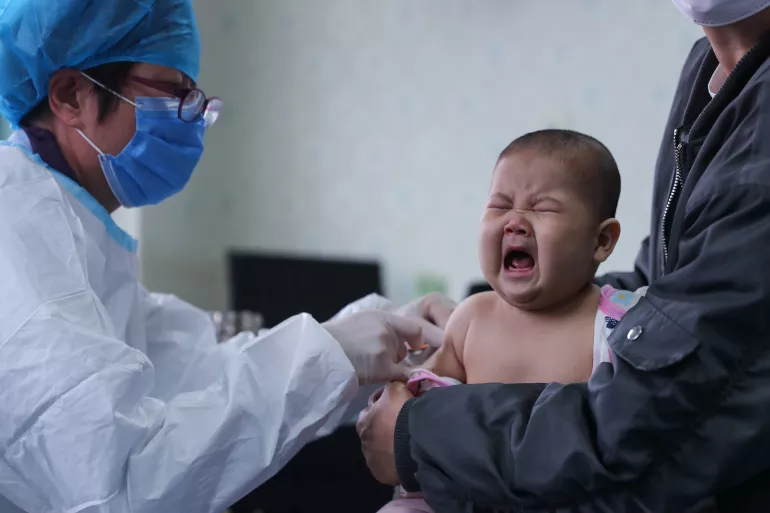 2020年3月26日，在北京市东城区朝阳门社区卫生服务中心，一名6个月的婴儿在补种疫苗。由于担心感染2019冠状病毒病，孩子的家长决定将百白破疫苗注射推迟。除湖北以外的地区正逐步恢复因2019冠状病毒病而调整或暂停的疫苗接种。