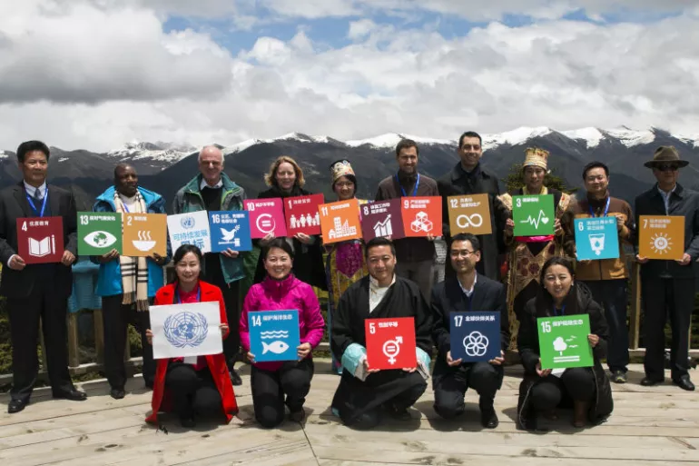 落实2030年可持续发展议程国际研讨会在西藏自治区林芝举行，与会代表与当地群众一起，在鲁朗林海观景台举起#可持续发展目标#。