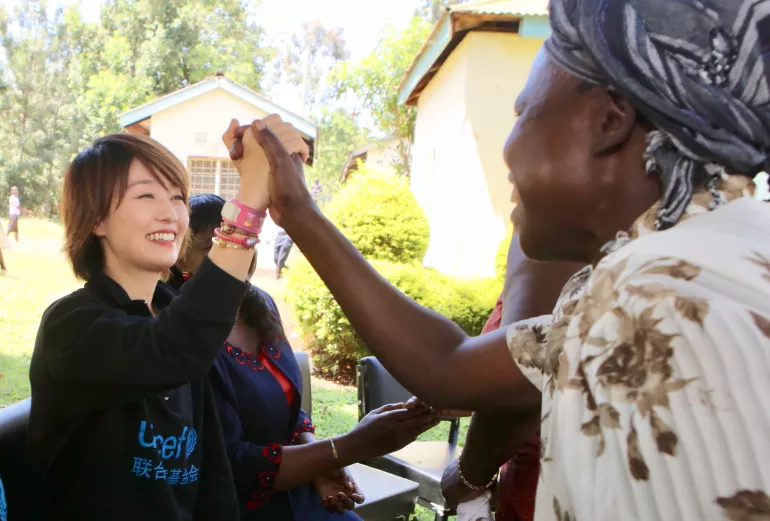 A community member invites UNICEF ambassador Ma Yili to join them during a meeting at Nyahera Village of Kenya's Kisumu County in August 2018. UNICEF works with Kenya's Ministry of Health and its partners to promote exclusive breastfeeding.