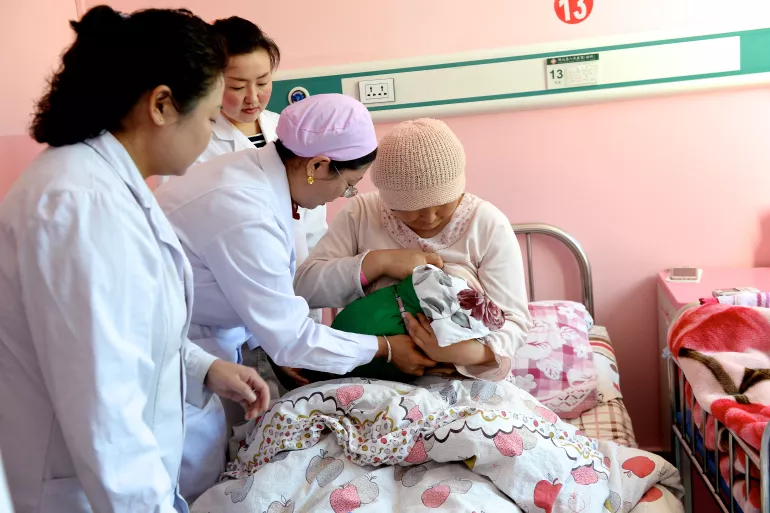 A doctor shows a woman how to properly breastfeed her baby at a hospital in Xunhua county, Qinghai Province, China.