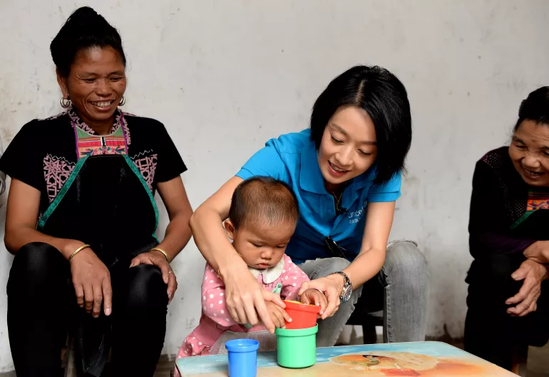 United Nations Children's Fund (UNICEF) Ambassador, Ma Yili, visits and plays with a child, who has been left behind by her migrating parents, at her home in Huanggang Village, Liping County in Guizhou Province.
