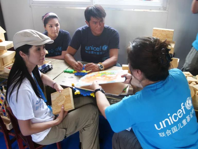联合国儿童基金香港委员会大使杨采妮、杨千嬅和古天乐（从左至右）在联合国儿童基金会支持建立的“儿童友好家园”内向儿童保护项目官员陈学锋女士了解孩子们的情况。