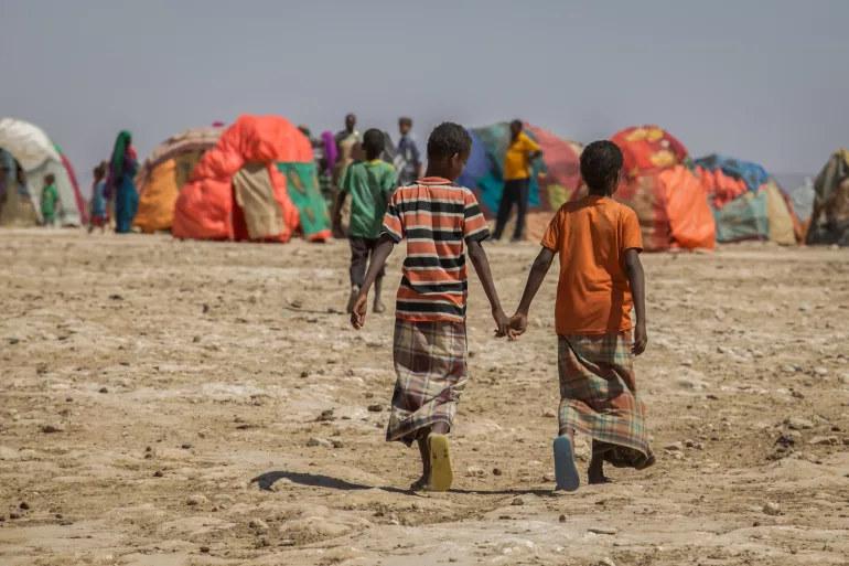两名男孩走回临时居住点，他们所在地区遭受了严重的旱灾。
