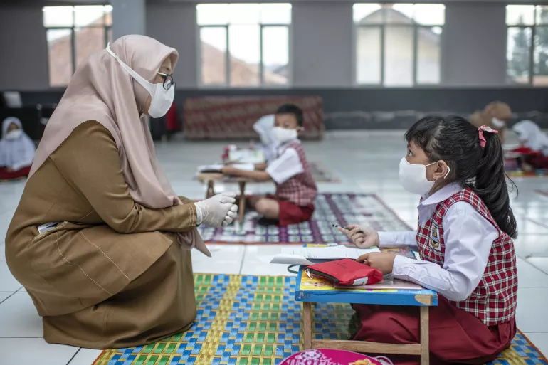 Nayla, 7, a student at in primary school, asks her teacher a question during class at the local village hall in Bandung, West Java province, Indonesia.