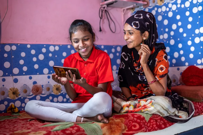 2019冠状病毒病疫情期间，印度的一位母亲在学校关闭时帮助女儿进行线上学习。