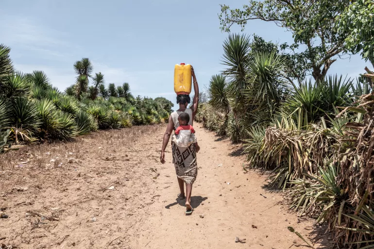 Claudine and her child heading back to their home in Mantara, Madagascar, after walking 14km to find water.