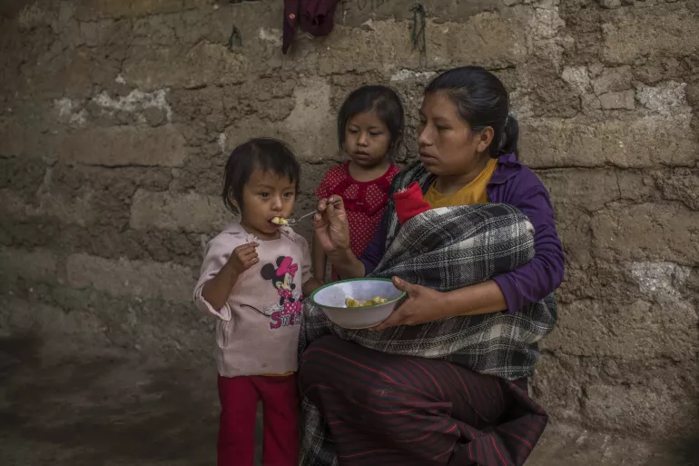Maria is feeding crushed bananas to her daughter Mariela.