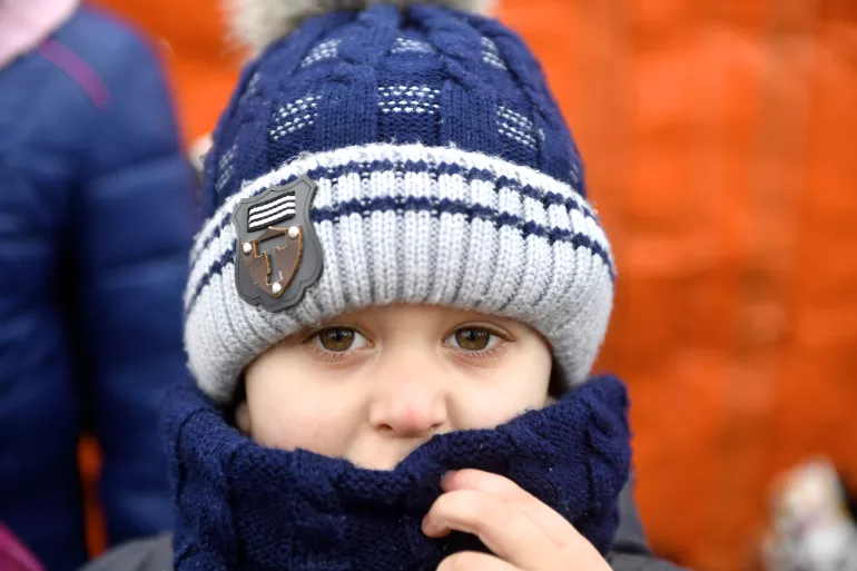 在乌克兰，一名戴着帽子和穿着夹克的儿童看着相机镜头。