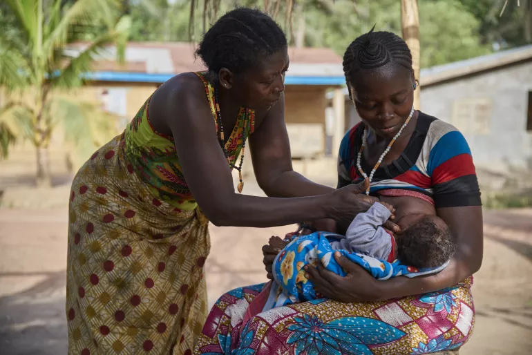 On 3 April, (right) Zainab Kamara, supported by her mother, breastfeeds one of her twin sons, 3-month-old Alhassan Cargo, in Karineh Village in Magbema Chiefdom, Kambia District.