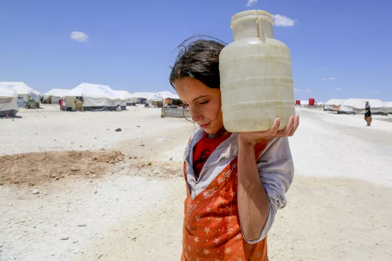 2017年6月3日，叙利亚阿拉伯共和国拉卡北部50公里处阿伊莎临时营地里，12岁的Horriya扛着一罐水。