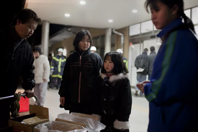 A girl and her parents queue for water in an emergency evacuation centre for people affected by the earthquake and in Fukushima Prefecture, Japan.