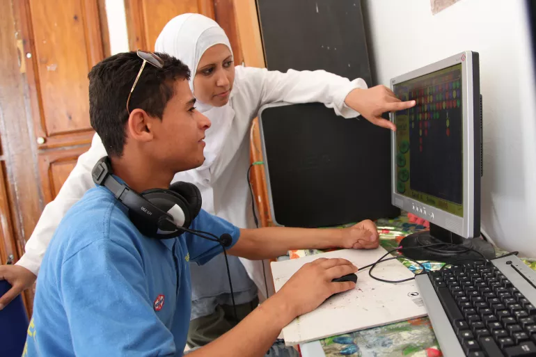 一位有心智残障的青少年在创新工作人员的帮助下学习操作一种特殊的计算机。