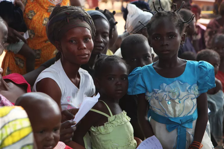 在中非共和国首都班吉，收容所里满是因战乱而背井离乡人们，一位年轻的母亲和她的孩子们正在等待接受疟疾检测。