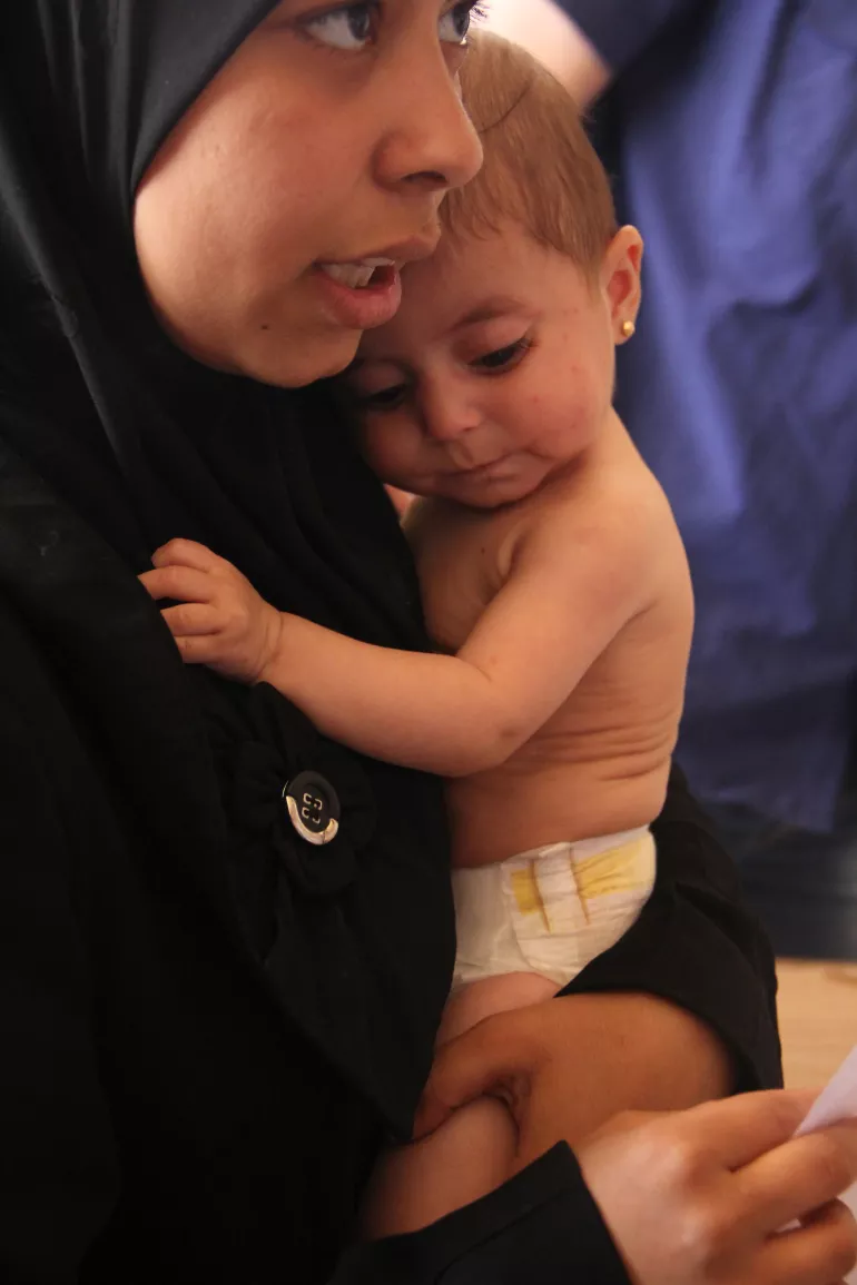 November 2014, Syria, a mother was holding her daughter who was receiving malnutrition treatment at a UNICEF supported clinic.